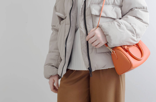 woman in  short down jacket with an orange handbag - Foto, imagen