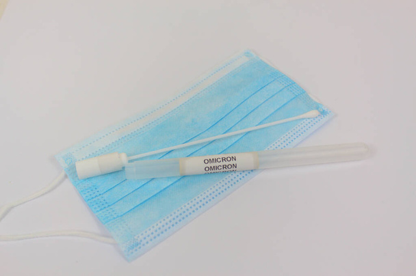 COVID-19 Omicron Nasopharyngeal probe container and medical face mask close-up view with white background - 写真・画像