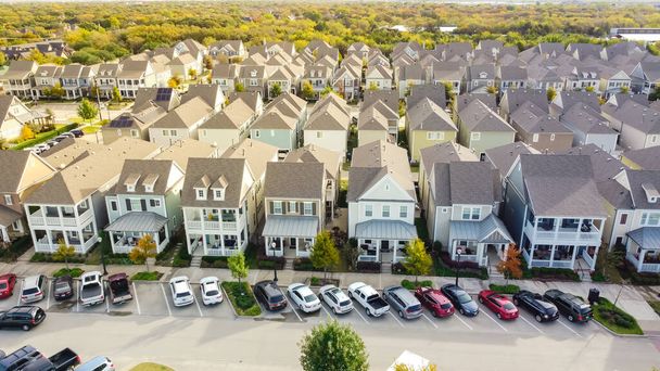 Eine Reihe gehobener Häuser im Landhausstil mit geparkten Autos auf der Straße in der Nähe der historischen Altstadt von Coppell, Texas, USA. Gehobene zweistöckige Häuser mit überdachter Veranda, üppig grüner Baumhintergrund - Foto, Bild