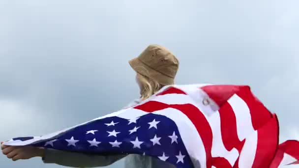 Victoria. La joven patriótica feliz ha levantado una bandera americana en sus manos. Viajes femeninos disfrutando de la vista senderismo aventura vacaciones al aire libre estilo de vida activo - Metraje, vídeo