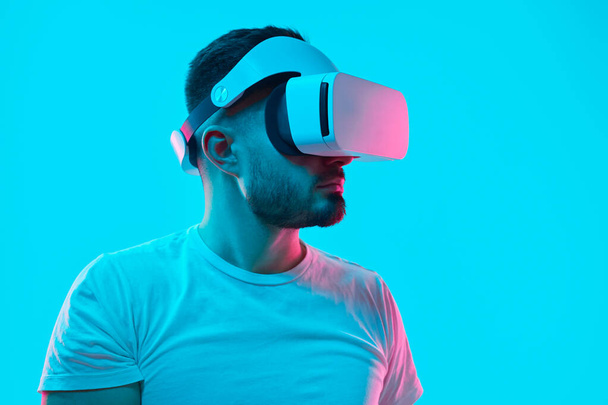Uomo serio in VR occhiali in studio con luci al neon - Foto, immagini