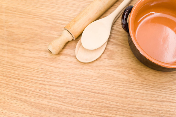 natural terracotta bowl and wood kitchen utensils on a wooden background with copy space - Foto, Imagem