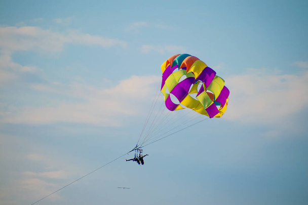 The tourist parasailing with the help of security in the cloudy sky on a sunny day - Fotó, kép