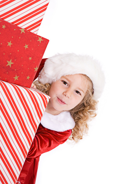 Christmas: Cute Santa Girl Peeks Around Stack Of Gifts - Foto, Imagen