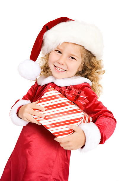 Christmas: Cute Girl In Santa Hat Carrying Gift - Foto, Bild