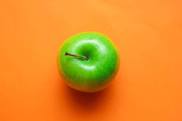A top view of a fresh ripe green apple isolated on an orange background - Fotografie, Obrázek