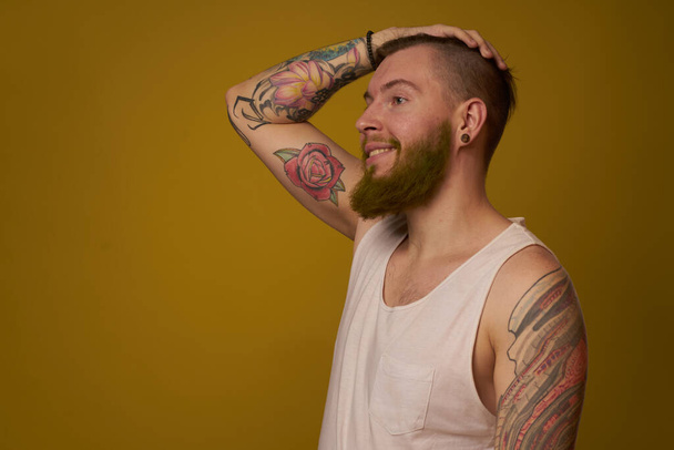 macho man in white t-shirt tattoos on his arms posing isolated background - 写真・画像