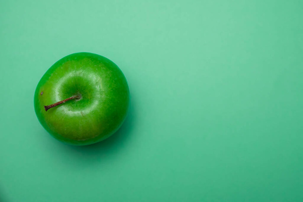 A top view of a ripe green apple isolated on a green background - Foto, afbeelding