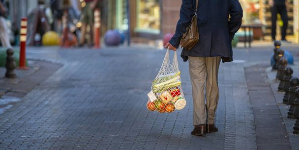 A man carrying a mesh shopping bag on a street - Fotó, kép