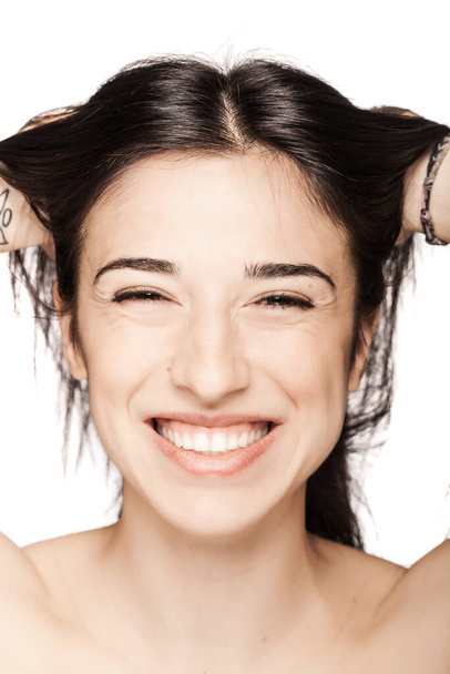 studio portrait of a beautiful brunette girl smiling against white backgroung. - Fotó, kép