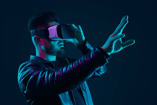 Man in VR glasses interacting with cyberspace in dark studio - Photo, image