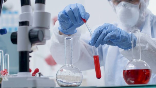 Chercheur scientifique médecin avec équipement ppe tenant des éprouvettes analysant des échantillons de sang - Photo, image