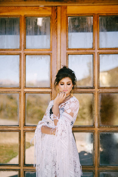 Dantel elbiseli genç kadın cam kapının yanında duruyor. - Fotoğraf, Görsel