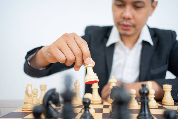 Мужская рука держит пешку за ногу во время игры в шахматы - Фото, изображение