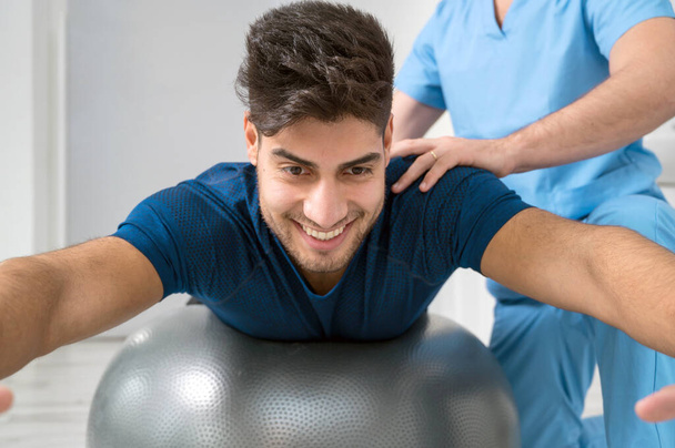 Fisioterapista aiuta bel giovane paziente con esercizi di pilates. - Foto, immagini