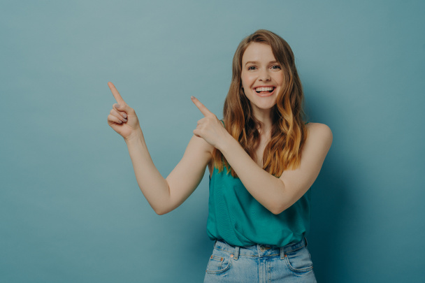 Pozytywna podekscytowana kobieta wskazuje na prawą stronę palcami obu rąk podczas reklamy produktu - Zdjęcie, obraz