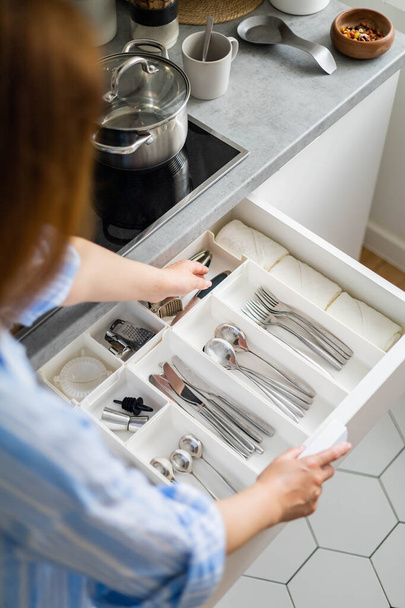 Top view closeup housewife hands tidying up cutlery in drawer general cleaning at kitchen - Φωτογραφία, εικόνα