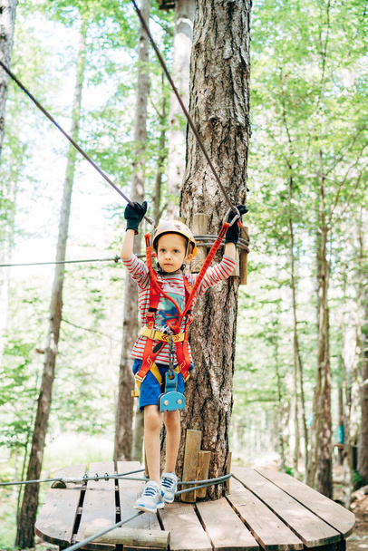 Boy stand on the zip line holding on to the safety cables - Photo, Image