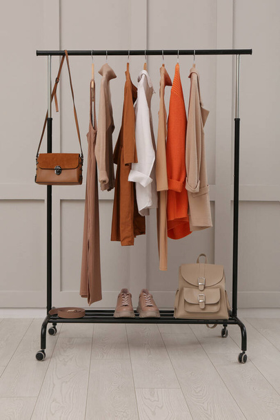 Rack with stylish women's clothes, shoes and accessories near light wall in room - Fotoğraf, Görsel