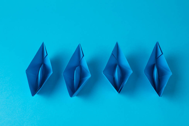 Handmade paper boats on light blue background, flat lay. Origami art - Foto, afbeelding