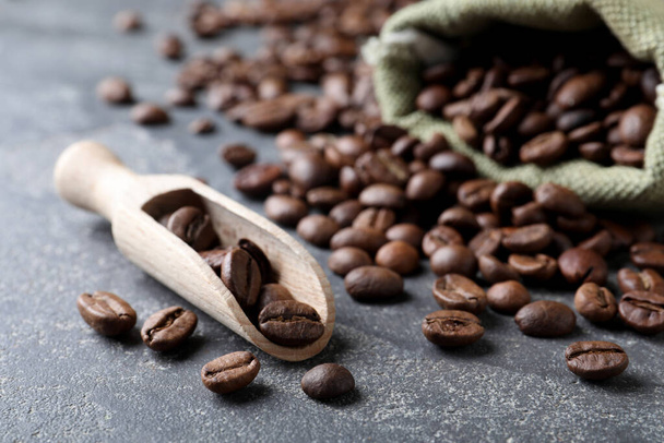 Wooden scoop and bag with roasted coffee beans on grey table, closeup - Valokuva, kuva