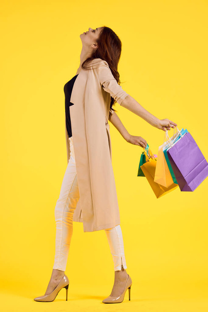 pretty woman with multicolored bags posing yellow background - Zdjęcie, obraz