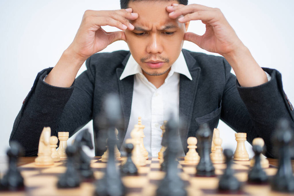Dizzy man wearing suit thinking about chess pieces moves - Fotó, kép