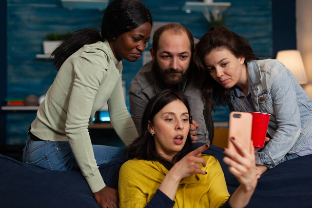 Amigos multiétnicos mirando videos fuuny en Internet usando un teléfono inteligente - Foto, Imagen