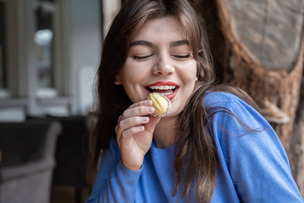 Μια νεαρή γυναίκα τρώει μπισκότα σε σχήμα καρυδιού.. - Φωτογραφία, εικόνα