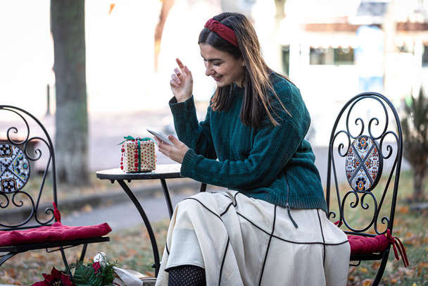 Привлекательная молодая женщина использует смартфон, рождественские покупки онлайн. - Фото, изображение