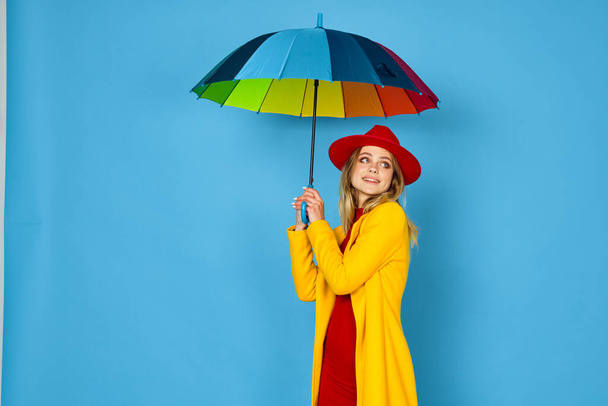 woman in yellow coat multicolored umbrella posing blue background - Foto, Imagem