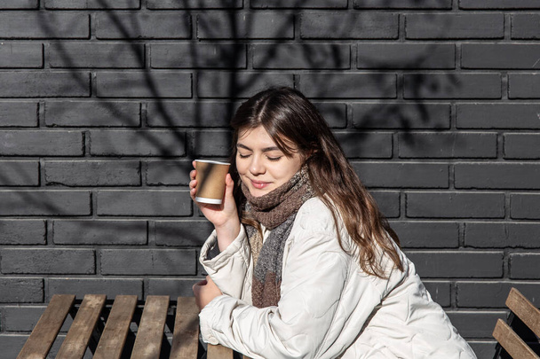 Jeune femme dégustant un verre contre le mur de briques de l'extérieur du café. - Photo, image