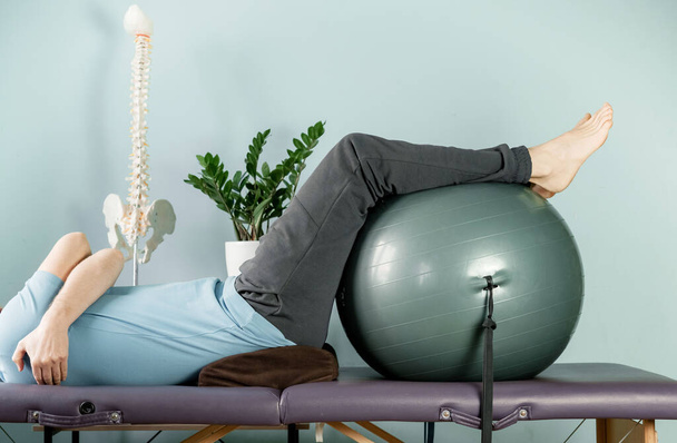Мужчина, лежащий на массажном столе в позе конструктивного отдыха, боли в суставах - Фото, изображение