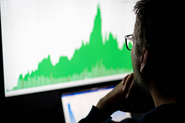 Crypto trader investor analyst looking at computer screen analyzing financial graph data on pc - 写真・画像