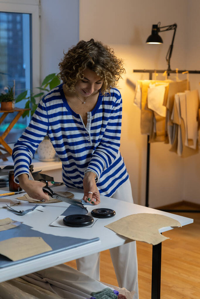 Vrouw op maat gesneden kleding monsters van patroon ontwerpen papier in kledingfabriek ontwerp atelier - Foto, afbeelding