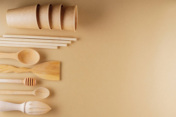Set of eco friendly wooden bamboo cutlery on beige background. Plastic free concept. Disposable paper cups and wooden kitchenware on earth color background. Zero waste concept - Foto, Imagem