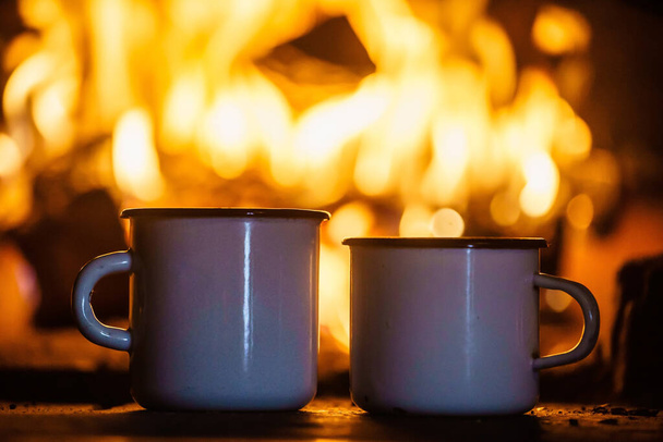 Tea mug with burning flame on hearth and fireplace indoors.  - Fotoğraf, Görsel