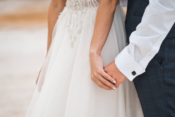 The newlyweds tenderly hold hands. - Foto, afbeelding