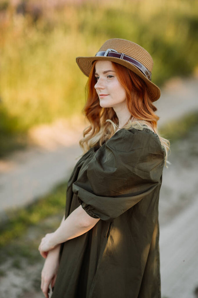 A large portrait of a red-haired girl in a green dress in the summer outside the city. - Foto, imagen