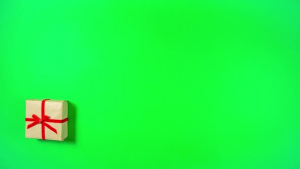 4k Weihnachtsgeschenkbox in Bastelpapier gewickelt und mit rotem Band gebunden bewegt sich dynamisch zu Rahmen mit Kopierraum in der Mitte des Rechtecks zu bilden. Grüner Hintergrund. Flach lag er. Kopierraum. Stop-Motion-Animation. - Filmmaterial, Video