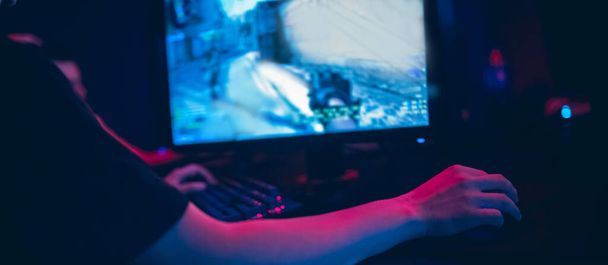 Professionelle Spieler spielen Online-Spiele Turniere PC-Computer mit Kopfhörern, verschwommener roter und blauer Hintergrund - Foto, Bild