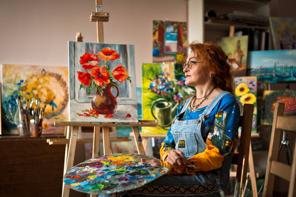 An experienced artist works in her own studio. - Фото, изображение