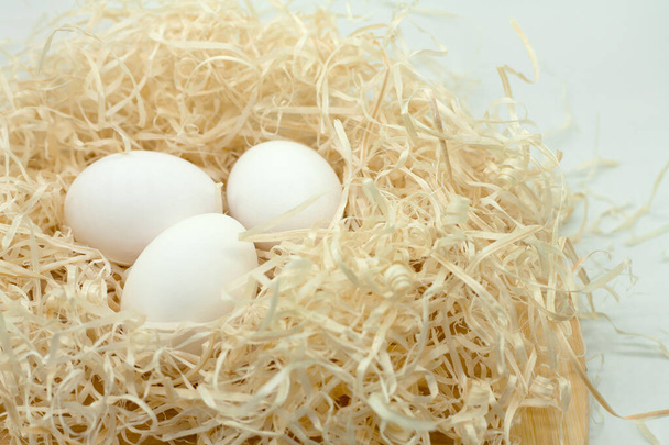 Three white eggs in wood shavings. - Photo, Image