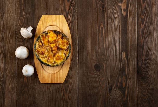 チーズとキノコの自家製ジュリアン。木製のテーブルの上に焼きチーズクラストと熱い料理. - 写真・画像