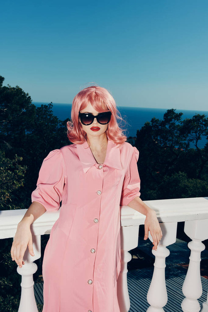 elbűvölő nő rózsaszín ruha modern stílus áll közel a korlát Relaxációs koncepció - Fotó, kép