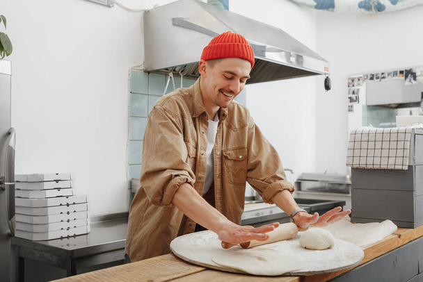 young chef makes the dough in the cafe - Foto, afbeelding
