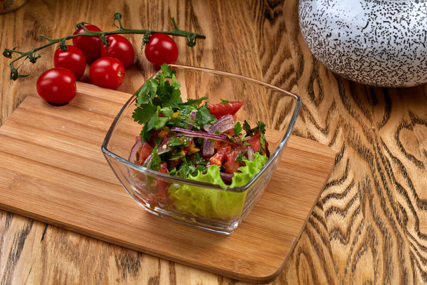 Uzbek salad achichuk with tomatoes and pepper on wood table - Фото, зображення