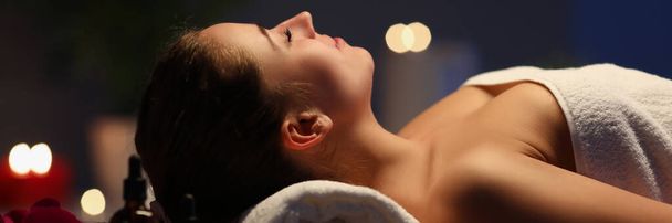 mujer se encuentra en la mesa de masaje en sala de spa oscuro - Foto, imagen