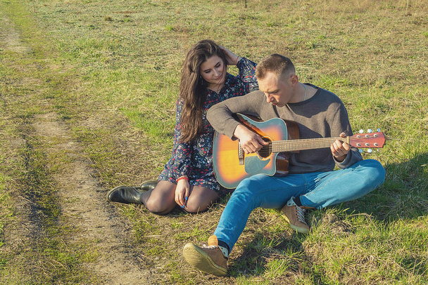 Ten chlap hraje na kytaru a ta holka sedí vedle něj a poslouchá. Venkovní rekreace - Fotografie, Obrázek
