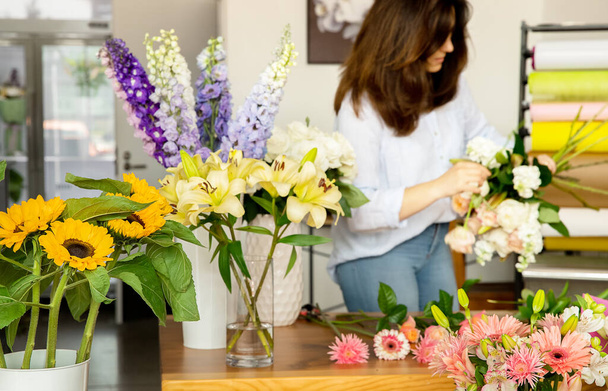 Klein bedrijf. Vrouwelijke bloemist in bloemenwinkel. Floral design studio, het maken van decoraties en arrangementen. Bloemen levering, het creëren van orde  - Foto, afbeelding